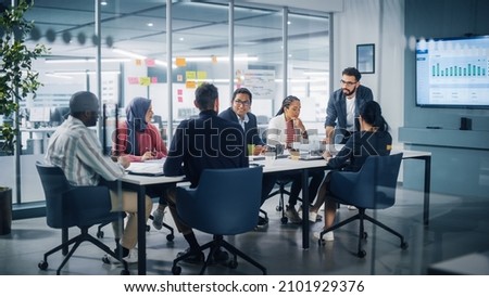 Multi-Ethnic Office Conference Room Meeting: Diverse Team of Young Entrepreneurs, Specialists Talk, Use TV for infographics. Smiling Businesspeople Discuss Investment Strategy in e-commerce Startup Royalty-Free Stock Photo #2101929376