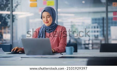 Modern Office: Portrait of Young Muslim Businesswoman Wearing Hijab Works on Laptop, Does Data Analysis, Website Design, Creative Development. Digital Entrepreneur Works on e-Commerce Startup Project Royalty-Free Stock Photo #2101929397