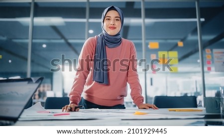 Modern Office: Portrait of Muslim Businesswoman Wearing Hijab Works on Engineering Project, Does Document and Blueprints Analysis. Empowered Digital Entrepreneur Works on e-Commerce Startup Project Royalty-Free Stock Photo #2101929445
