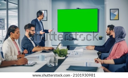 Office Conference Room Meeting Presentation: Indian Businessman Talks, Uses Green Screen Chroma Key Wall TV. Digital Entrepreneur Presenting a Product to Group of Multi-Ethnic e-Commerce Investors