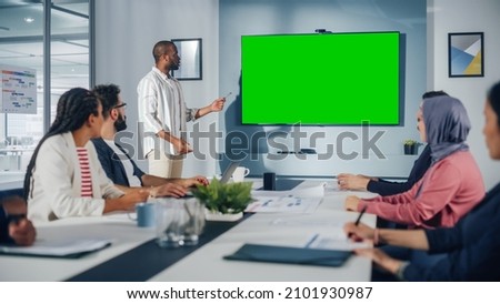 Office Conference Room Meeting Presentation: Black Businessman Talks, Uses Green Screen Chroma Key Wall TV. Successfully Presenting a Product to Group of Multi-Ethnic Investors. e-Commerce Strategy