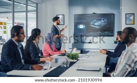 Multi-Ethnic Office Conference Room Meeting: Hispanic Industrial Engineer Presents Car Concept to a team of Technicians Talk, Use TV with 3D Vehicle Prototype Concept. Eco-friendly, Green Energy Royalty-Free Stock Photo #2101930996