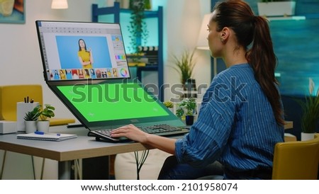 Professional editor working with green screen and retouching app. Woman with isolated background and mockup template editing pictures on computer. Chroma key in photography studio