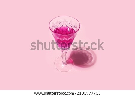 Pink cocktail alcohol drink in a wine glass isolated on pastel pink background. Romantic feminine fashion party or valentines day minimal concept banner.