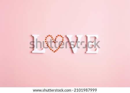 Word love with a heart instead of the letter O on a pink background. Happy Valentine's Day concept