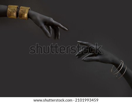 Black woman's hands with gold jewelry. Oriental Bracelets on a black painted hand. Gold and silver Jewelry and luxury accessories on black background closeup. High Fashion art concep