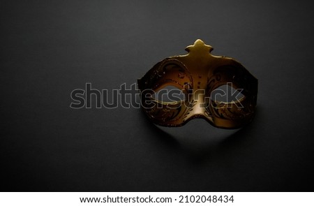 Gold carnival mask on a dark background. Mystery, minimalism, elegance