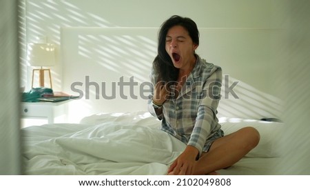 Woman waking up in the morning sitting in bed yawning. Person wake up Royalty-Free Stock Photo #2102049808