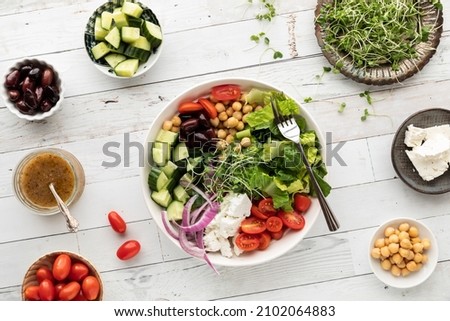 Top down view of a Greek salad bowl with separate bowls of the ingredients. Royalty-Free Stock Photo #2102064883