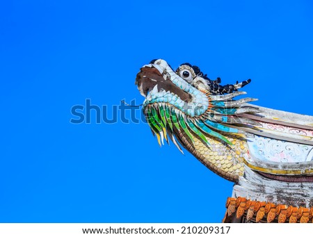 Dragon statue on the roof of a public Chinese temple with blue sky background