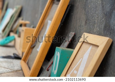 A closeup of children's wooden toys and picture frames leaning against a blackboard in a classroom