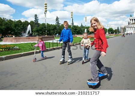Friends riding a skateboard and scooter in park