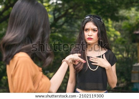 A woman is offended by the accusations of a another young lady, claiming to have cheated or scammed her. Royalty-Free Stock Photo #2102119300