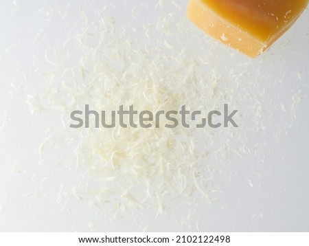 Whole and grated italian hard cheese Grana Padano or Parmesan isolated on white background. Delicious ingredient for pizza, sandwiches, salads. Front view.                