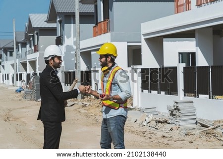Architects or project-managers, punch-to-punch with home builders egineer welcome the completion of the construction and greet each other as friends in a housing project under construction.  Royalty-Free Stock Photo #2102138440