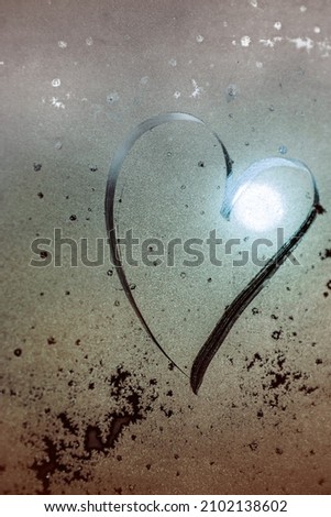 Heart, symbol of a beautiful heart with the sun inside painted on misted glass, moonlight, texture of frost and water drops, empty space for an inscription. vertical frame