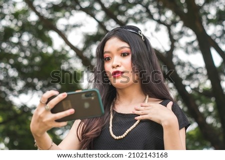 A young woman surprised and taken aback by a scandalous social media post. Online gossip, an offensive post or fake news. Royalty-Free Stock Photo #2102143168
