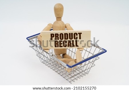 Business and finance concept. A wooden man sits in a shopping basket, holding a sign in his hands - PRODUCT RECALL