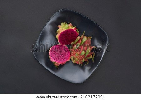 Fresh dragon fruit on black plate. Taken from the top view some distance away                              