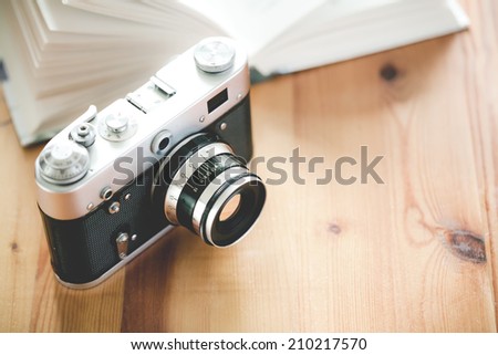 Old vintage camera with book on a wooden table.