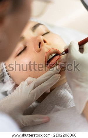 Professional permanent makeup artist and her client during lip blushing procedure Royalty-Free Stock Photo #2102206060