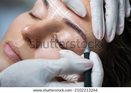 Young woman during professional eyebrow mapping procedure before permanent makeup Royalty-Free Stock Photo #2102213266