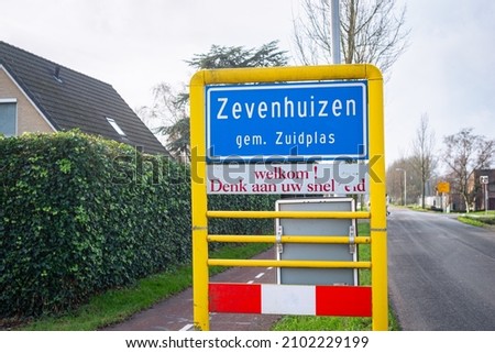 Place name sign of Zevenhuizen, municipality of Zuidplas, The Netherlands. Sign below says "Welcome! Think about your speed" in Dutch. Focus on foreground.