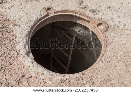 An open manhole on the road. Dangerous open unsecured hatch on the road. Accident with sewer hatch in city. Concept of sewage, repair of underground communications Royalty-Free Stock Photo #2102239438