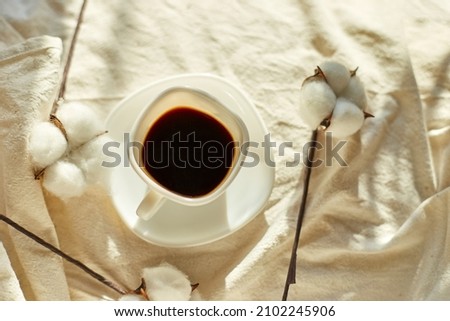 Cup of coffee in bed with cotton flowers,  morning mood, Organic and natural linen cotton textile bedclothes, copy space.