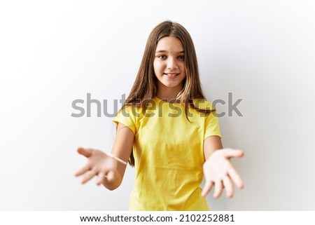 Young brunette teenager standing together over isolated background smiling cheerful offering hands giving assistance and acceptance. 