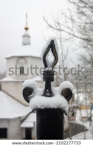 Decorative metal fence, in winter in a snowy park landscape.