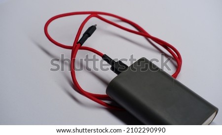 Power bank for mobile phones with red usb charging cable isolated on a white background