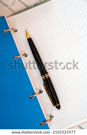 blue notebook with black ballpoint pen, upright, diagonal arrangement