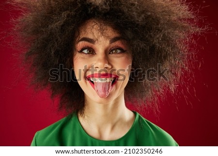 Positive young woman with curly hair grimace posing emotion red background unaltered