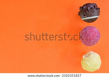 Collection of chocolate sweets on a colorful background. Chocolate pralines on an orange background with copy space. Flat lay, top view.