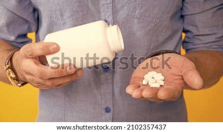 cropped man hold vitamin jar on yellow background, vitamins