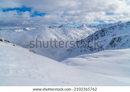 Amazing alpine panoramic view in Livigno, Italy with clouds below snowy peaks
