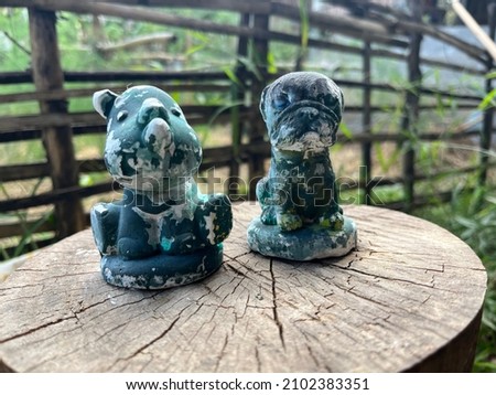 Plaster figures of Red and a small dog painted in green.