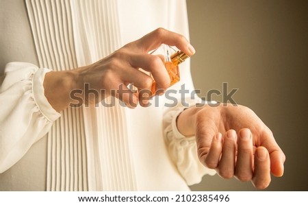 Young woman testing and applying parfume Royalty-Free Stock Photo #2102385496