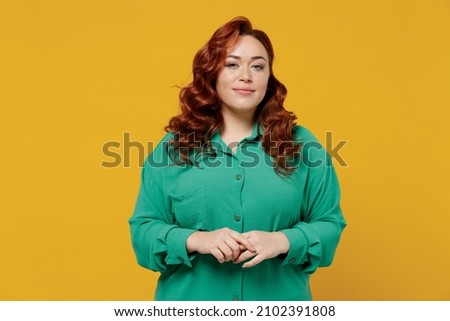 Charming bright happy young ginger chubby overweight woman 20s years old wears green shirt looking camera smiling isolated on plain yellow background studio portrait. People emotions lifestyle concept Royalty-Free Stock Photo #2102391808