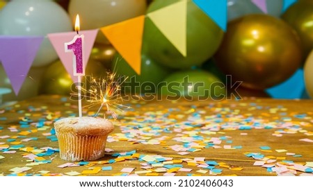 Cupcake with candle, Happy birthday greeting card to baby 1 year old, birthday cupcake with candles and birthday decorations. Copy space