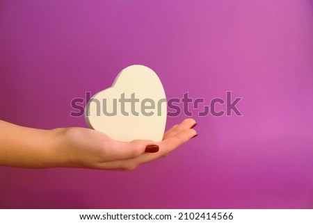 girl's hand with white heart on purple background