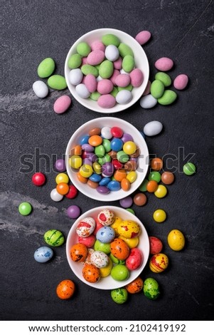 Multicolored glaze dragee or candies for fun party on black marble background