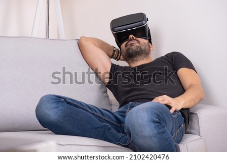 Young man using VR glasses headset at home on sofa, Virtual reality, future technology, education video gaming.