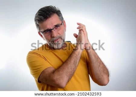 Handsome senior bearded guy posing in studio - isolated on grey background. Mature man with beard wearing t-shirt and glasses over grey background clapping and applauding happy and joyful.
