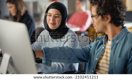 Female Muslim Student Wearing Hijab, Studying in Modern University with Diverse Multiethnic Classmates. She Asks Scholar a Question in College Room. Learning Software Engineering or Computer Science. Royalty-Free Stock Photo #2102451211