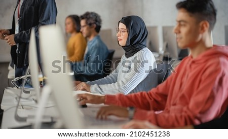 Female Muslim Student in Hijab, Studying in University. She Works on Desktop Computer in College with Diverse Multiethnic Classmates. Applying Her Knowledge to Acquire Academic Skills in Class.