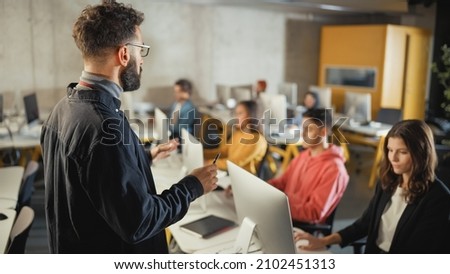 Teacher Giving Lesson to Diverse Multiethnic Group of Female and Male Students in College Room, Learning New Academic Skills on a Computer. Lecturer Shares Knowledge with Smart Young Scholars. Royalty-Free Stock Photo #2102451313