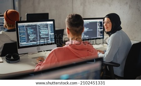 Smart Young Students Studying in University with Diverse Multiethnic Classmates. Scholars Collaborate in College Room on Computer Science Project, Writing Software Code in Successful Teamwork. Royalty-Free Stock Photo #2102451331