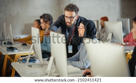 Lecturer Helps Scholar with Project, Advising on Their Work. Teacher Giving Lesson to Diverse Multiethnic Group of Female and Male Students in College Room, Teaching New Academic Skills on a Computer. Royalty-Free Stock Photo #2102451421
